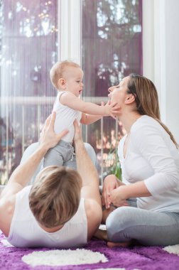 Döşeme ve katta oturan ve onların bebek çocuk ile mutlu anne. Onun çocuğunu tutan baba.