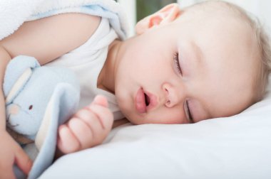 Yatağında bırakmasını ve uyuyan güzel bebek çocuk. Yakın çekim.