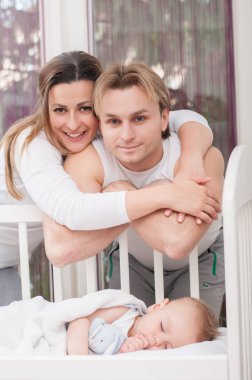 Mutlu anne bebeğin yatağın yanında duruyor. Mutluluk ve gurur.