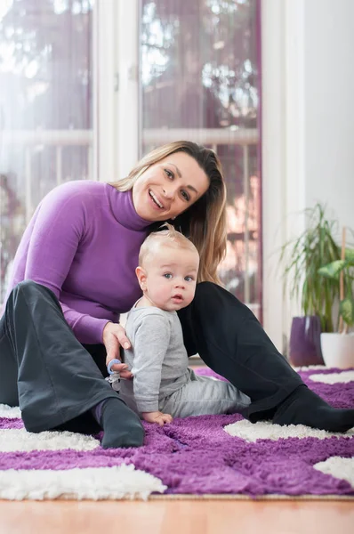 床に座って 彼女の男の子と一緒に遊んで幸せな母 — ストック写真