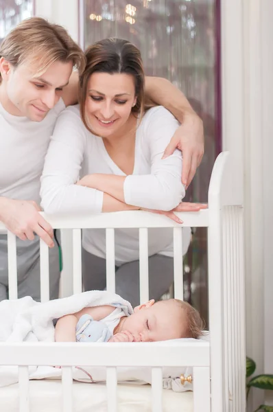 幸せな親は 赤ちゃんのベッドの横に立っています 幸福と誇り — ストック写真