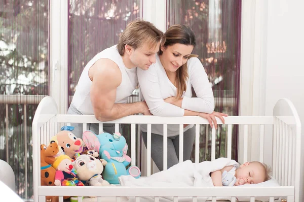 幸せな親は 赤ちゃんのベッドの横に立っています 幸福と誇り — ストック写真