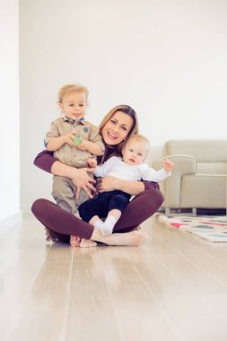 Mutlu anne iki bebeklerini ile katta oturan ve müzik