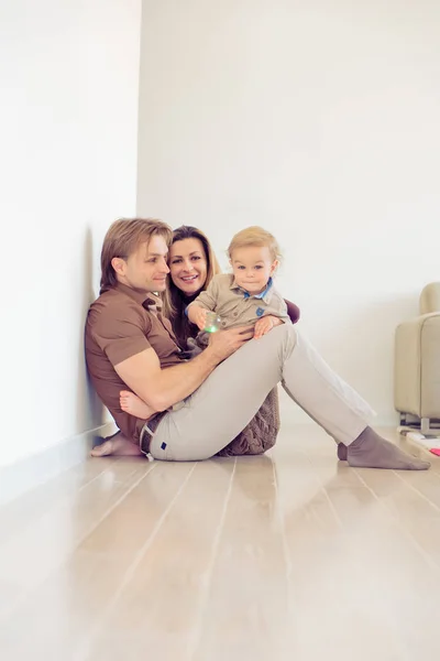 Famiglia felice seduta sul pavimento con il loro bambino piccolo. Famiglia trascorrere del tempo a casa con il figlio . — Foto Stock