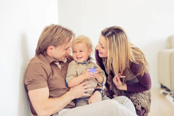 Щаслива сім'я сидить на підлозі зі своєю дитиною. Сімейний час вдома зі своїм сином . — стокове фото
