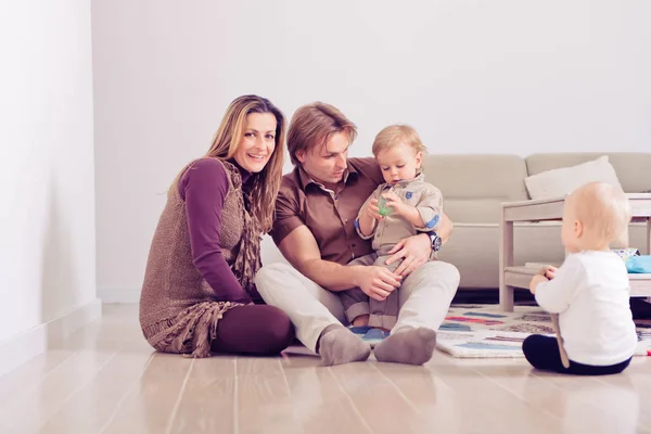 Famiglia felice seduta sul pavimento con i loro bambini piccoli Famiglia che trascorre del tempo a casa con il figlio e la figlia . — Foto Stock