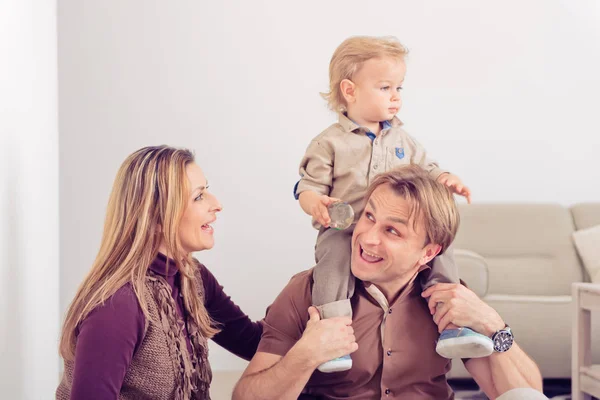 Famiglia felice seduta sul pavimento con il loro bambino piccolo. Famiglia trascorrere del tempo a casa con il figlio . — Foto Stock