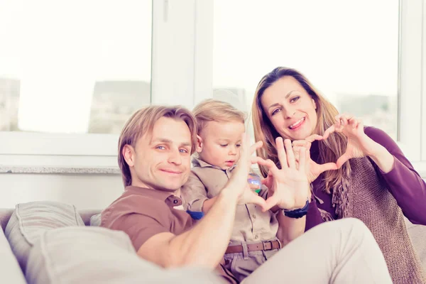 Портрет щасливої сім'ї, що сидить на дивані і посміхається. Серце — стокове фото