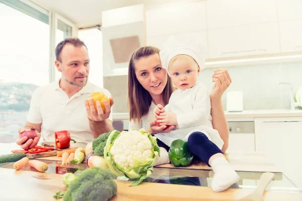 Glückliche Eltern sitzen in der Küche und bereiten sich auf das Kochen mit ihren kleinen Köchinnen vor. — Stockfoto