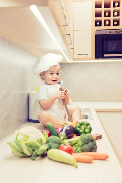 台所で野菜の中で座っている男の子し、料理の準備 — ストック写真