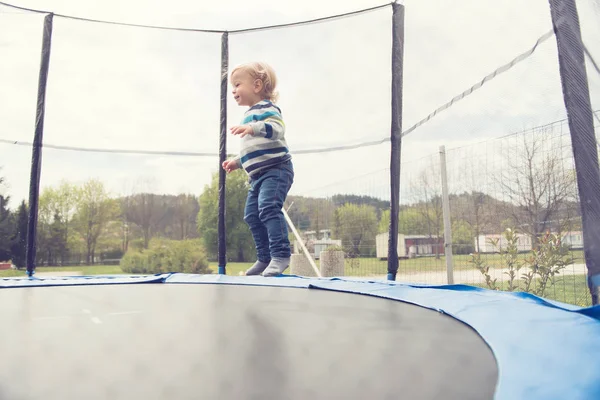 Hermoso niño saltando en el trampolín al aire libre . — Foto de Stock