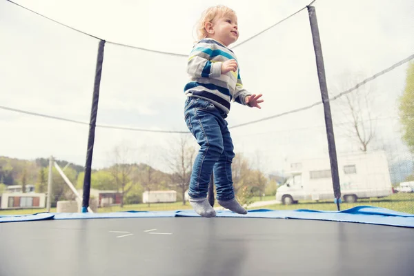 Vacker liten pojke hoppar på studsmattan utomhus. — Stockfoto