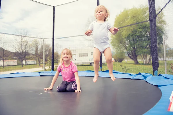 Två vackra barn hoppa på studsmattan och njuter. — Stockfoto