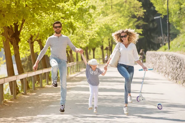 Lycklig far, mor och liten flicka hoppande kasta parken på en vacker solig dag. — Stockfoto