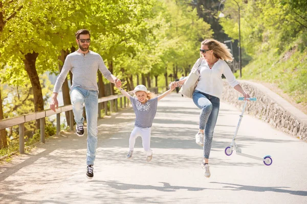 Buon padre, madre e bambina che saltano lanciano il parco in una bella giornata di sole . — Foto Stock