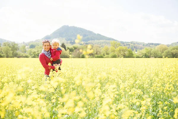 Felice madre che tiene il suo bambino nel campo in bella giornata di sole — Foto Stock