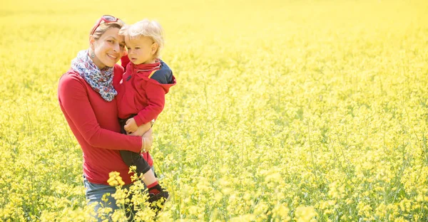 Felice madre che tiene il suo bambino nel campo in bella giornata di sole — Foto Stock