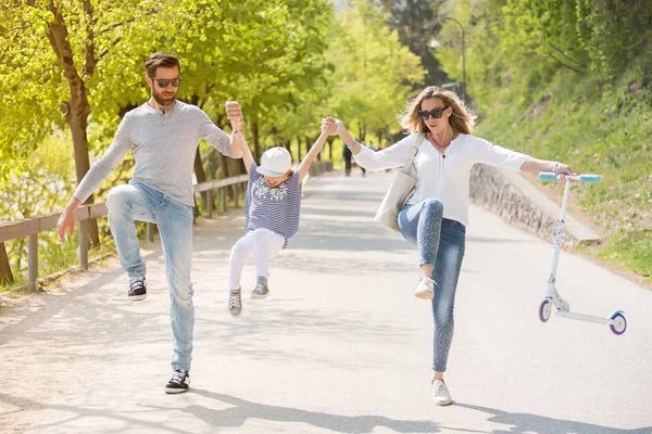 Buon padre, madre e bambina che saltano lanciano il parco in una bella giornata di sole . — Foto Stock