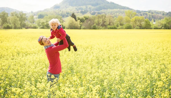 Щаслива мати тримає свого маленького хлопчика в полі в красивий сонячний день — стокове фото