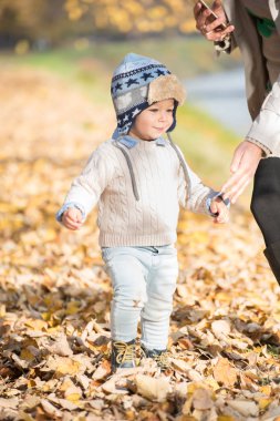 Güzel bebek çocuk yürüyen atmak parkta yaprak.