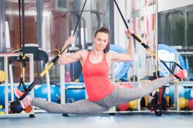 Trx üzerinde egzersiz yaparak güzel genç kadın.