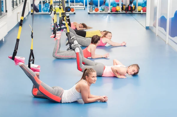 Grupo de belas mulheres jovens trabalhando no TRX. Tempo de descanso . — Fotografia de Stock