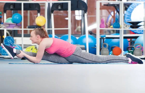 Güzel genç kadının gimnastics yerde yapması. — Stok fotoğraf