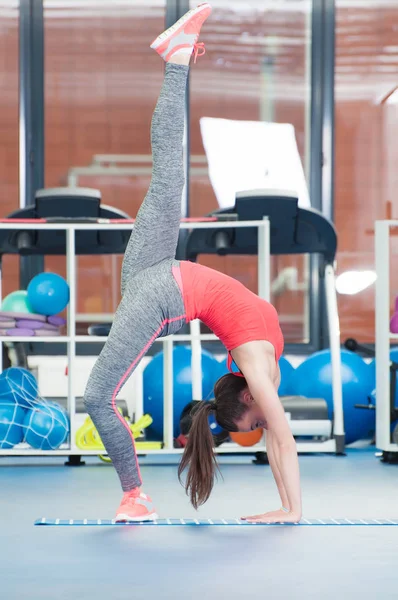 Όμορφη νεαρή γυναίκα να κάνει gimnastics στο πάτωμα. — Φωτογραφία Αρχείου