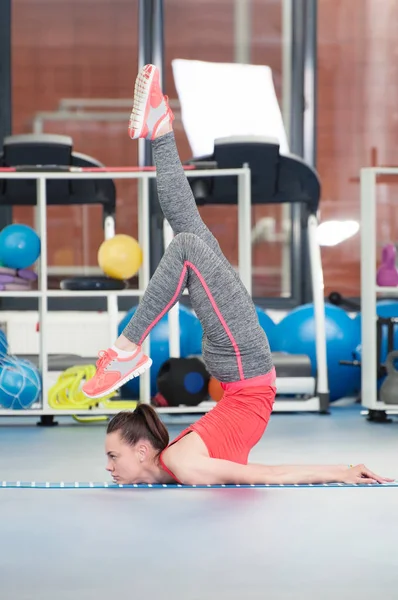 Όμορφη νεαρή γυναίκα να κάνει gimnastics στο πάτωμα. — Φωτογραφία Αρχείου