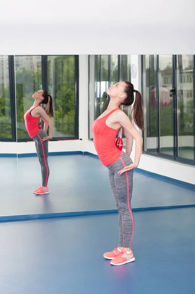 Krásná mladá žena dělá gimnastics na podlaze s palcáty. — Stock fotografie