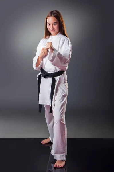 Hermosa joven jugador de karate femenino posando sobre el fondo gris — Foto de Stock