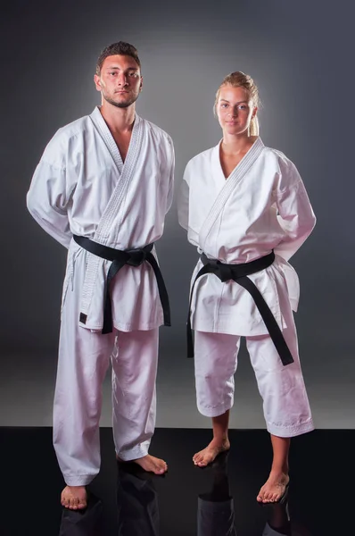 Dos jugadores de karate posando sobre el fondo gris — Foto de Stock