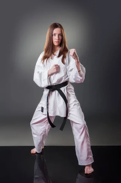 Gri arka planda poz güzel genç kadın karate oyuncusu — Stok fotoğraf