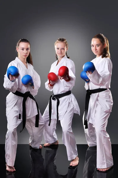 Grupo de hermosas jóvenes jugadoras de karate posando sobre el fondo gris — Foto de Stock