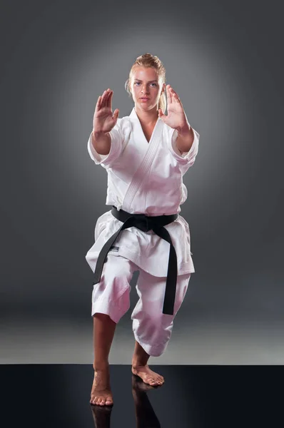 Hermosa joven jugador de karate femenino posando sobre el fondo gris —  Fotos de Stock