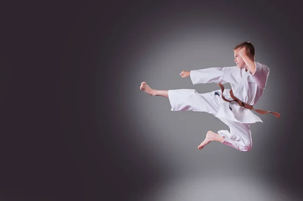 Przystojny młody męski Karate gracz robi kick na The szary backgro — Zdjęcie stockowe
