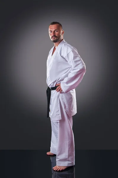Pohledný mužský hráč karate, který pózí na šedém pozadí — Stock fotografie