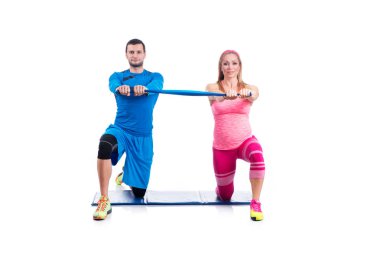 Mutlu genç çift beyaz arka plan üzerinde gebelik için elastik kauçuk ile çift egzersiz yapıyor.