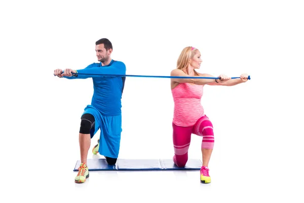 Šťastný mladý pár cvičením v páru s elastickou pryží pro těhotenství na bílém pozadí. — Stock fotografie