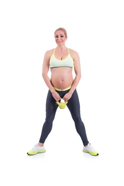 Hermosas mujeres embarazadas felices haciendo ejercicio con kettlebell en el fondo blanco — Foto de Stock