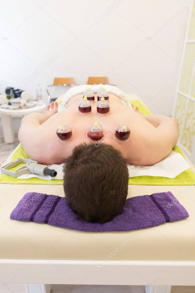 Young man laying down at the massage table and doing hijama treatment