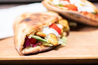 Ahşap bir tabak üzerinde ev yapımı baget ile Sağlıklı Izgara Tavuk Sandviç.