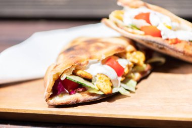 Ahşap bir tabak üzerinde ev yapımı baget ile Sağlıklı Izgara Tavuk Sandviç.