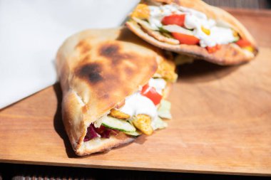 Ahşap bir tabak üzerinde ev yapımı baget ile Sağlıklı Izgara Tavuk Sandviç.