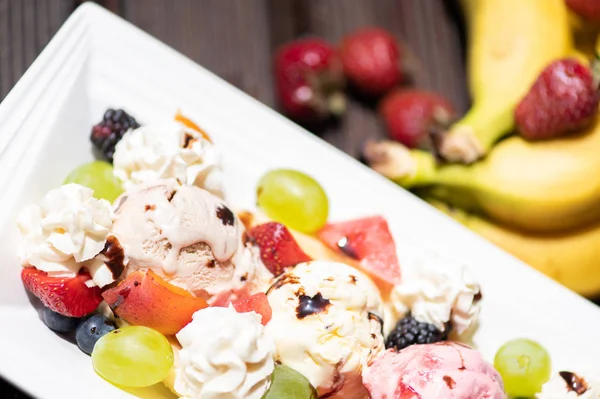 Ahşap arka plan üzerinde dondurma ile sağlıklı taze meyve salatası Tabak.