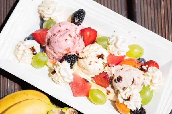 Ahşap arka plan üzerinde dondurma ile sağlıklı taze meyve salatası Tabak. Üstte görüntü. — Stok fotoğraf