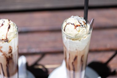 Odun bir masada krema dökülen buz kahvesi, içeceğin dokusunu ve ferahlatıcı görünümünü gösteriyor..