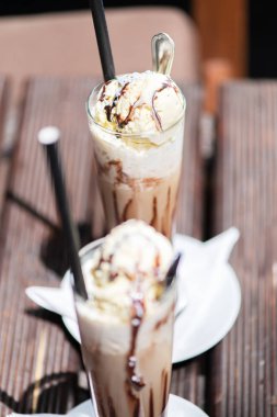 Odun bir masada krema dökülen buz kahvesi, içeceğin dokusunu ve ferahlatıcı görünümünü gösteriyor..