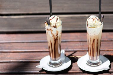 Odun bir masada krema dökülen buz kahvesi, içeceğin dokusunu ve ferahlatıcı görünümünü gösteriyor..