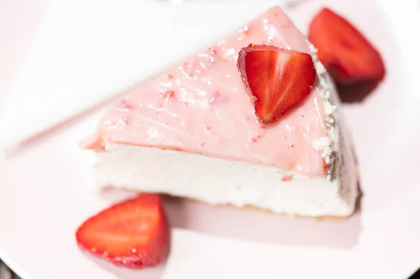 Шматочок свіжого полуничного пирога на рожевій тарілці з шаруватим кремом. Вид зверху . — стокове фото